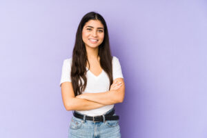 Young confident woman smiling on purple background
