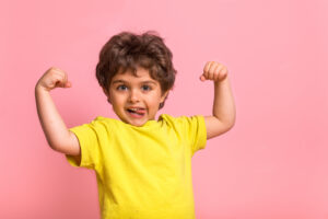 Boy showing off in yellow shirt on pink background