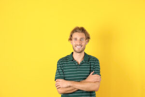 Handsome young man laughing on color background