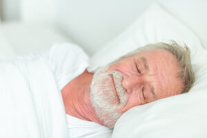 Happy senior man sleeping in bed.