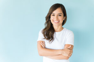 Charming Caucasian woman with arms crossed smiling against colored background
