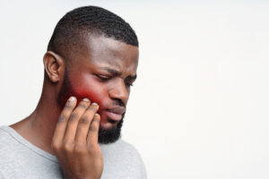 Young sad black man having pain in his teeth