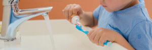 Happy kid or child brushing teeth in bathroom. Dental hygiene.